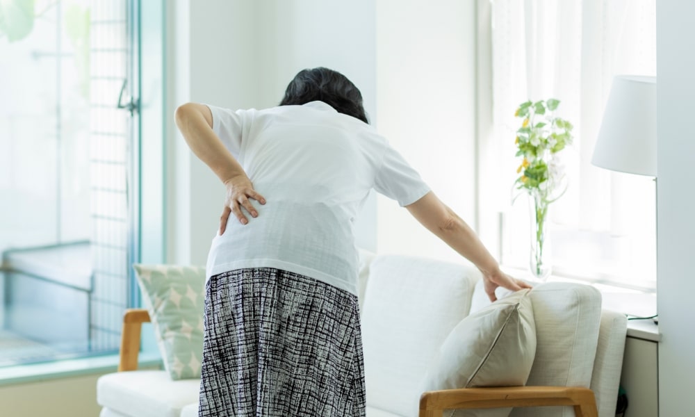 中腰でぎっくり腰の女性-min